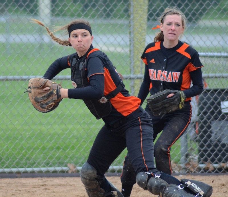 Warsaw catcher Kayla Snider makes a play as teammate Kara Dishman looks on Saturday.