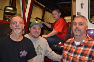 From left are Mentone Firefighters Tim Croy, Brandon Cody and Matt Cohagan. In the driver's seat of the fire truck is Branden Dugan. Dugan will get to attend Hoosier Burn Camp this summer thanks to the men of the Mentone Fire Department and the Kosciusko County Fire Association. (Photo by Stacey Page)