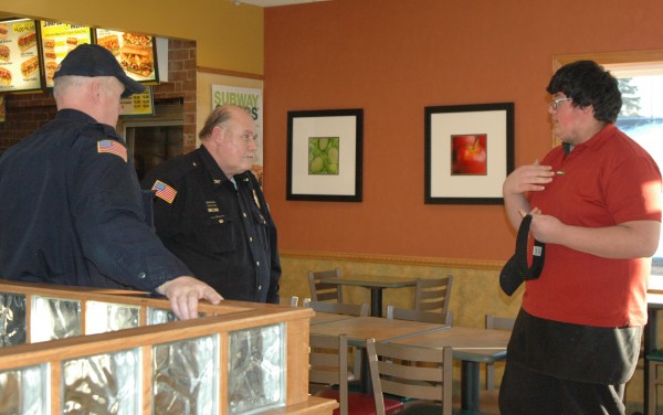 Milford Police Officer Tim Miller and town marshal Rich Miotto, speak with Gabriel Camarena, employee. Camarena was one of the last persons to leave the store on Sunday evening. (Photo by Chelsea Los)