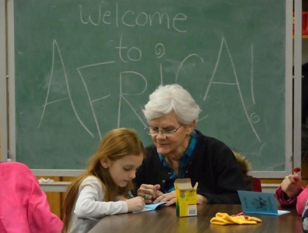 Pictured is volunteer “BIG Sister” Barbara Hull helping her “Little,” seven year old Gracie, complete her passport requirements for Around the World Night in Africa.