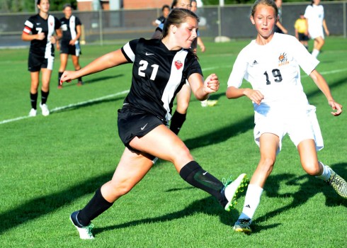 Manchester's Ellie Milam clears the ball from danger as Anna Reimink converges.