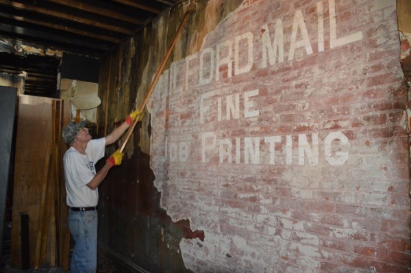 Leon Young works on chiseling away the layers of wall coverings inside the Turf Bar in Milford.