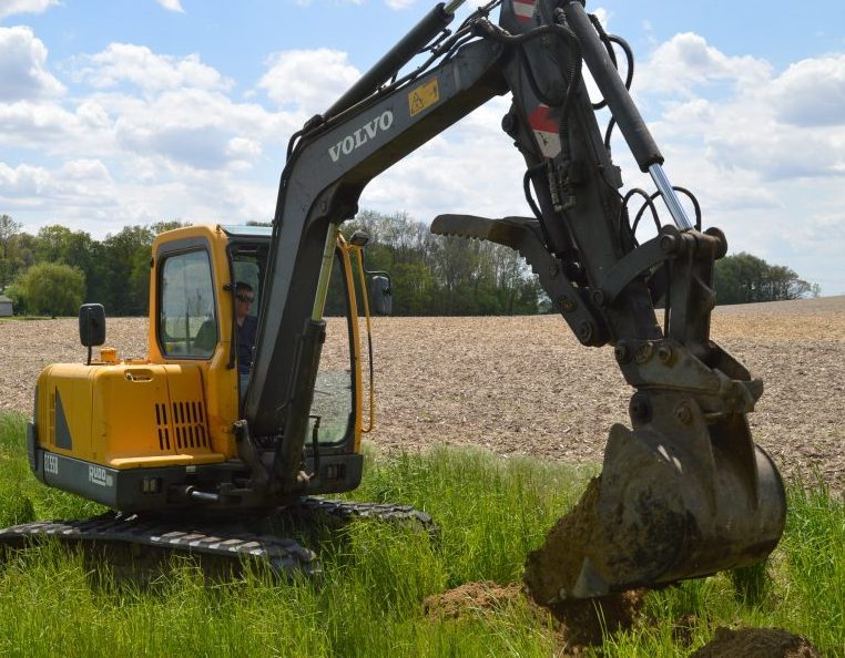 Chris Moyer of Good Excavating is using digging equipment in an attempt to locate a drainage tile originally installed in 1914 on property located in Prairie Township. Flooding has occurred on CR 700W, north of CR 550N, and the county surveyor’s office was called to address the problem. A nearby field was farmed when the drainage tile was installed but no longer is.